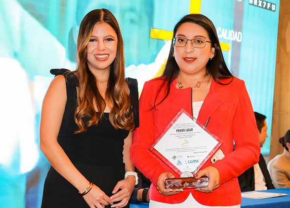dos mujeres vestidas de forma formal, recibiendo un premio