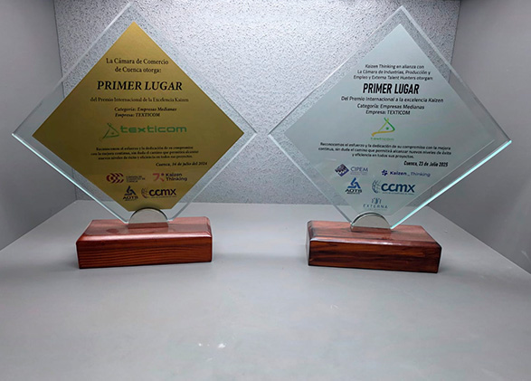 dos trofeos de vidrio y base de madera colocados sobre fondo gris en la muestran el primer lugar de empresa texticom